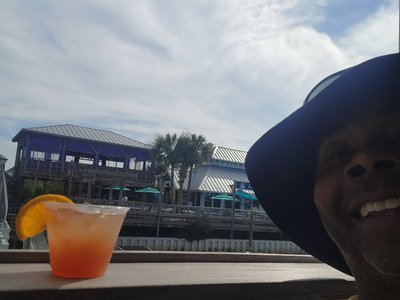 Waterfront view with a citrus cocktail overlooking the Bald Head Island harbor buildings.