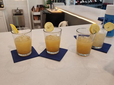 Flight of fresh citrus and bourbon cocktails garnished with lemon wheels on the bar counter.