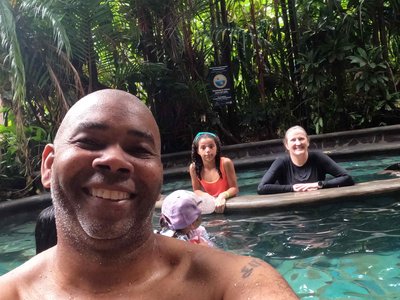 Group relaxing along the stone tier ledges in the 109°F mineral waters surrounded by tropical flora.