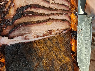 Full spread of carved brisket slices arranged on butcher paper next to a carving knife.